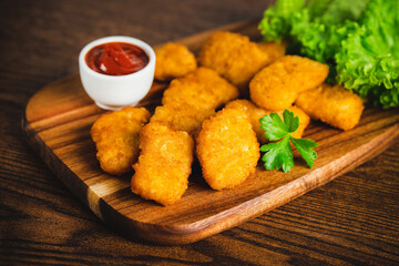 Chicken Breaded Raw Meat.Fast food.Fast cooking.Chicken nuggets with salad.Semifinished Breaded chicken nuggets from chicken fillet on a dark background with fresh herbs. Quick cooking at home.