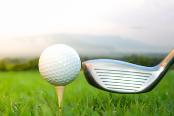 Golf ball set on tee and club head 1 mountain background.