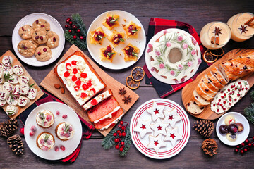 Christmas food table scene. Overhead view on a dark wood background. Group of appetizers and...