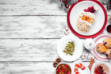 Christmas breakfast side border. Overhead view on a white wood background. Fun holiday food concept. Santa pancakes, scones, fruit and cereals. Copy space. - obrazy, fototapety, plakaty