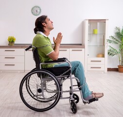 Young male invalid in wheel-chair suffering at home