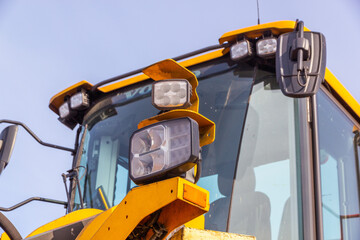 Close up view of the big yellow tractor. Headlight of the front end loader
