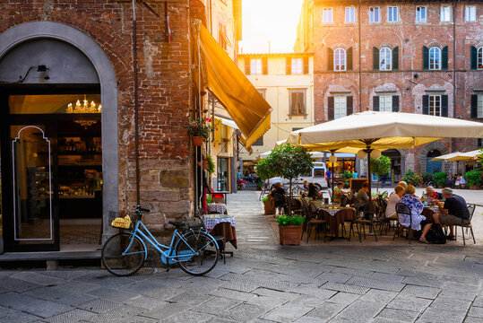 Fototapeta Old cozy street with tables of restaurant in Lucca, Italy
