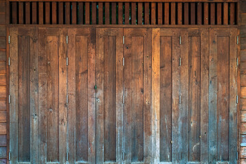 Traditional antique wooden folding door Asian style frame. Thai traditional wooden gate of historical architecture. Beautiful retro wooden folding door with lock under evening sunlight. Vintage Door.