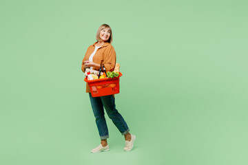 Full body side view elderly woman wear brown shirt casual clothes hold shopping paper bag with food...