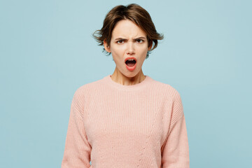 Young indignant mad furious sad woman wears beige knitted sweater casual clothes look camera with opened mouth isolated on plain pastel light blue cyan background studio portrait. Lifestyle concept.