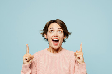 Young amazed woman she wear beige knitted sweater casual clothes point index finger overhead...
