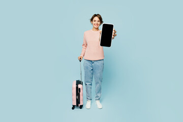 Traveler woman wear casual clothes hold bag blank screen mobile cell phone isolated on plain blue background . Tourist travel abroad in free spare time rest getaway. Air flight trip journey concept.
