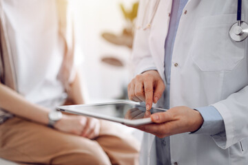 Doctor and patient in clinic. Friendly physician using tablet computer near a young woman. Medicine concept