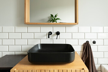 Industrial interior of bathroom with black ceramic washbasin on wooden cabinet, square mirror and...