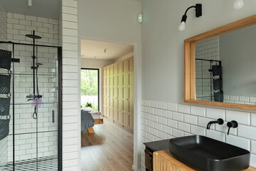 Modern bathroom with stylish black ceramic sink, industrial shower cabin and direct access to...