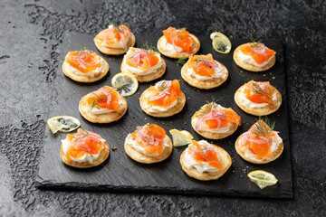 Mini blini pancakes with soft cheese, cold smoked salmon and dill