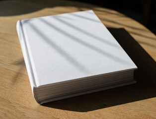 Book cover, blank hardback mockup laying on wooden table with sunlight, day light