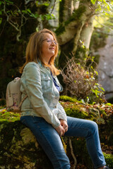 Portrait of senior white woman sitting resting in enchanted beech forest, Spain.