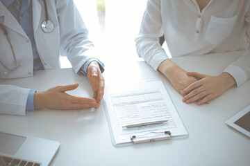 Doctor and patient discussing current health questions while sitting near of each other and using...
