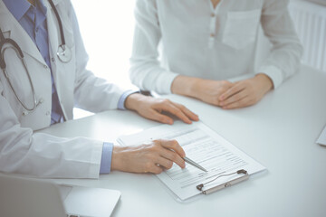 Doctor and patient discussing current health questions while sitting near of each other and using...
