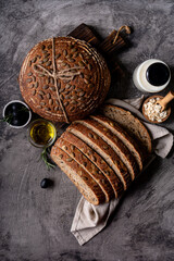 Baked sourdough bread from whole grain flour and pumpkin seeds on a grid, olive oil and black olive...