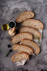 Baked sourdough bread from whole grain flour and pumpkin seeds on a grid, olive oil and black olive on a rustic wooden table. Artisan bread.