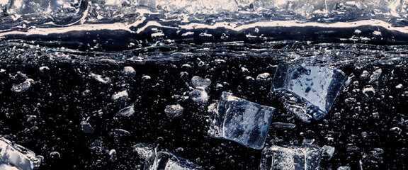 Water splashing and ice cube. Ice splashing into a glass of water. Underwater pouring ice cubes...