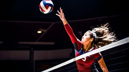 An Asian volleyball player passing the ball over the net - obrazy, fototapety, plakaty