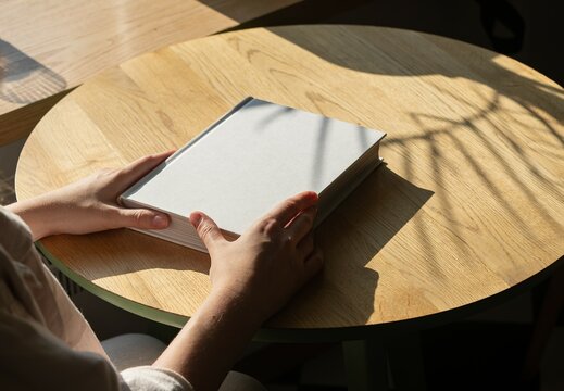 Hands on book mockup, lying on wooden table
