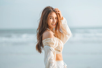 Fototapeta na wymiar Summer beach vacation concept, Carefree young asian woman relaxing at tropical sea beach during summer vacation, Smiling female enjoying breeze and looking at beach.