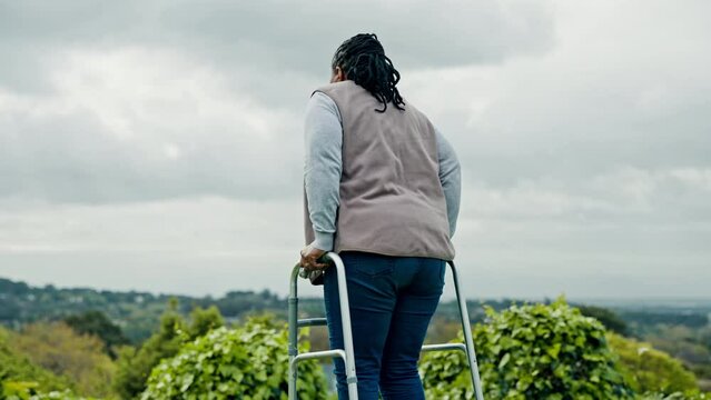 Black woman, senior with walker and retirement, walking outdoor in garden with fresh air and nature. Environment, person with disability and rehabilitation, elderly care and back view in countryside