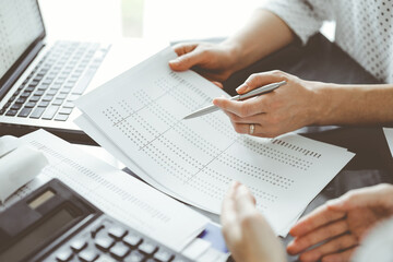 Female accountant pointing with a pen into audit paper while explaining tax counting results, close up. Business audit and finance concepts