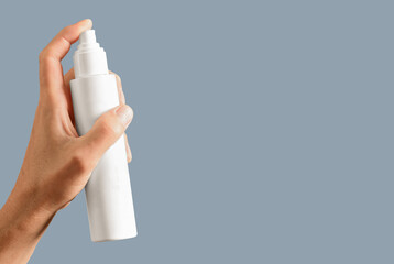 Male hand spraying lotion from bottle package mock up, white blank clean cosmetic pack on banner...