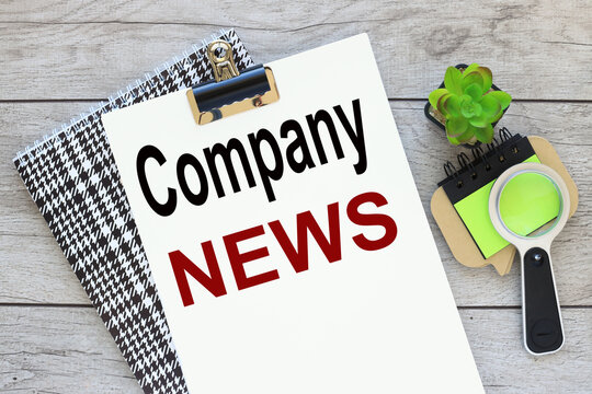 Company NEWS light wooden background. text on notebook. magnifying glass on a bright sticker