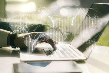 Double exposure of abstract digital world map with connections and hands typing on laptop on...