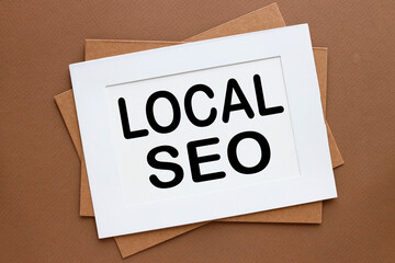 top view of a white page in a paper frame .brown background. words LOCAL SEO