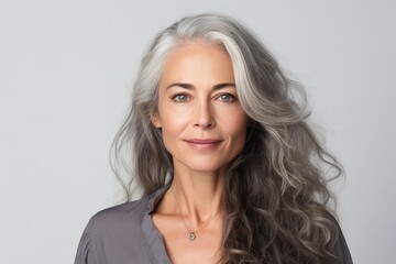 A cheerful and stylish mature Caucasian woman with beautiful grey hair, exuding confidence and happiness in a studio portrait.