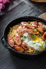 4K Image: Top View of Flavorful Ramen Noodles with Sausage and Egg in a Cast Iron Pan