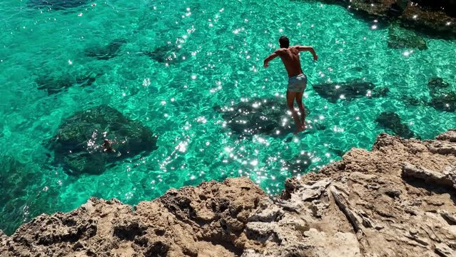 Adventurous spirit takes a daring cliff jump into Minorca's crystal-clear waters slow motion