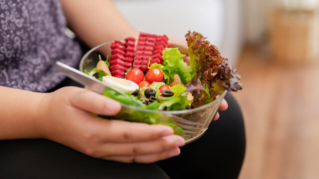 Overweight Woman Enjoy Eating A Bowl Of Vegetable Salad At Her Home.