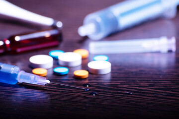 Closeup of injection syringe with medicine pills on table