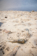 The bottle lies in the sand. Garbage lies on the sand. Polluted beach. Polluted nature