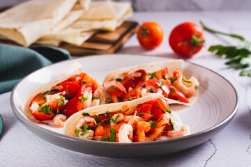 Vegetarian mini tacos with tomatoes, shrimp and herbs on a plate on the table