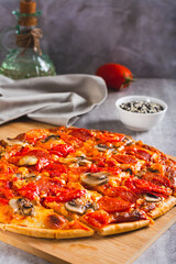 St. Louis Style pizza with bacon, mushrooms, tomatoes and peppers on a board vertical view