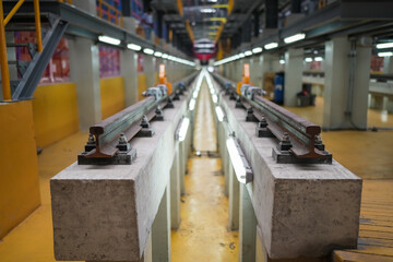 Instructor and apprentices under train in railway engineering facility