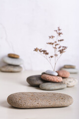 A podium made of smooth sea stone and a dried flower from a pile of stones vertical view