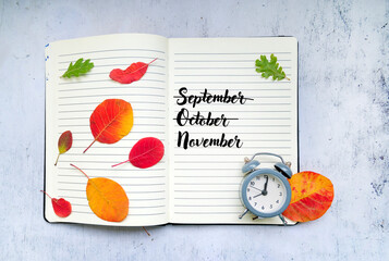 September ,October ,November written on notebook with autumn leaves 