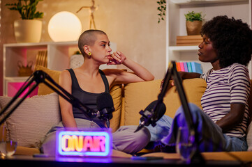 Couple of diverse women recording episode of internet podcast in a modern studio
