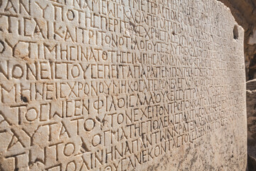Historical inscription (the text of law at Ancient Greek language). Carving on marble block. Selcuk, Turkey (Turkiye). Retro background - obrazy, fototapety, plakaty