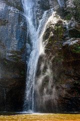 Fototapeta na wymiar Waterfall water running down dark rocks lit by the sun in the state of Minas Gerais, Brazil