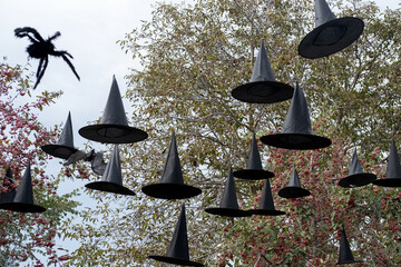 Halloween decorations outsaid. Black hats, spiders fly in the air, outdoors.