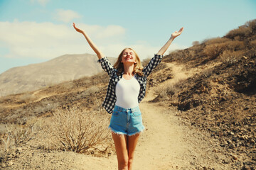 Happy cheerful young woman raising her hands up on hiking trail on top of the mountain, Tenerife, Canary Islands, Spain - obrazy, fototapety, plakaty