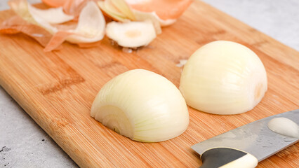Peeling and cutting white onion on a cutting board. Vegetable soup recipe. Ingredients close-up