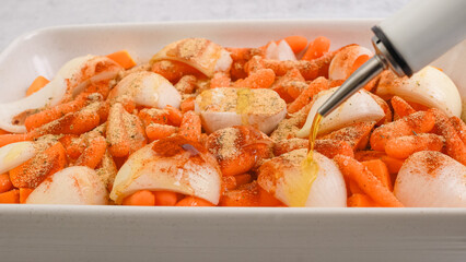 Roasted butternut squash soup recipe. Peeled and seedless squash cubes, carrot, onion, garlic, and spices close-up in a ceramic baking dish